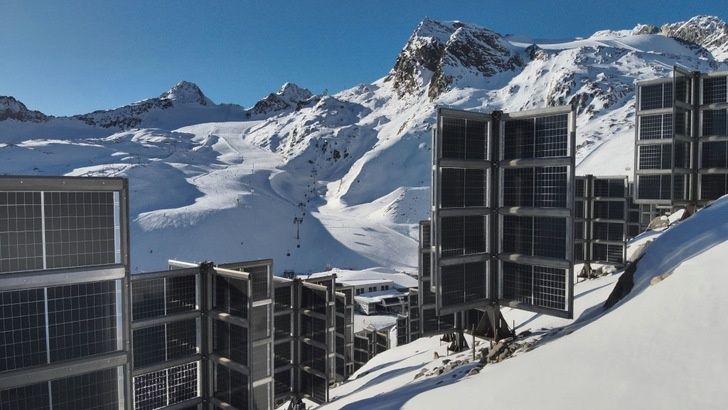 Large solar panel arrays installed on a snowy alpine mountainside