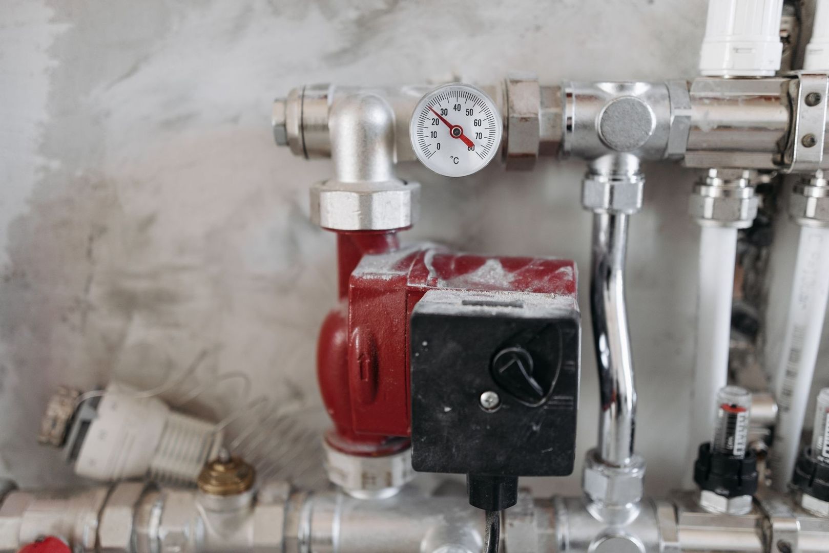 Heating system pipes with a red circulation pump and temperature gauge