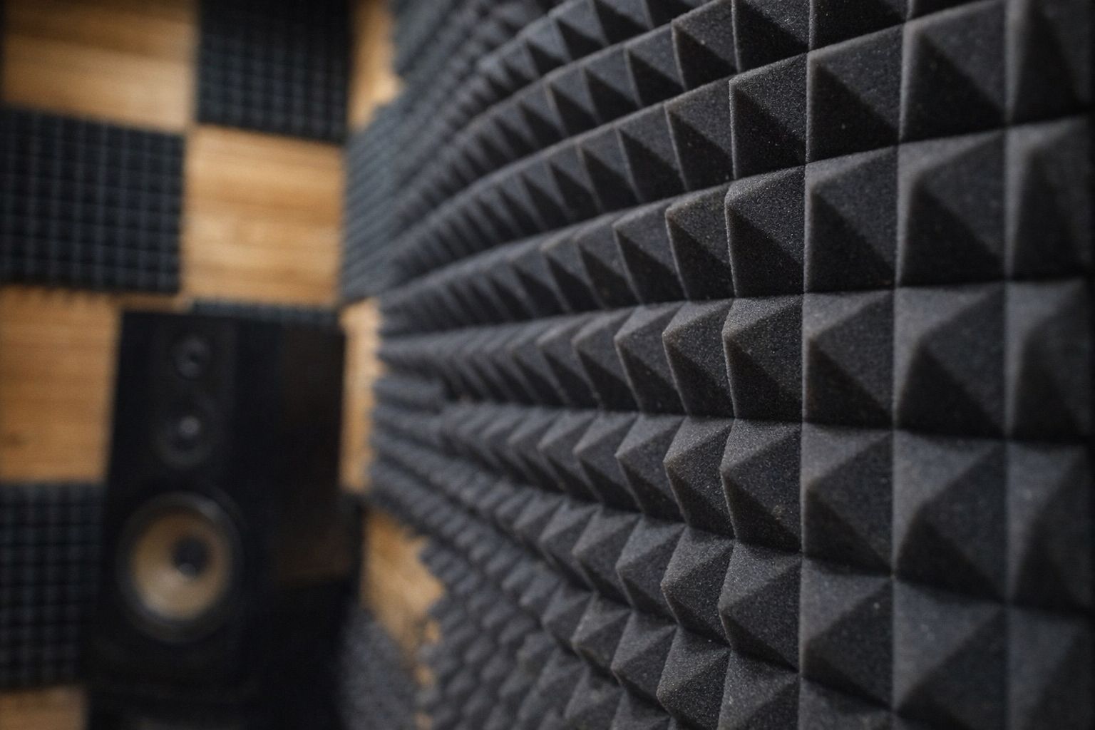 Close-up of black pyramid acoustic foam panels in a recording studio.